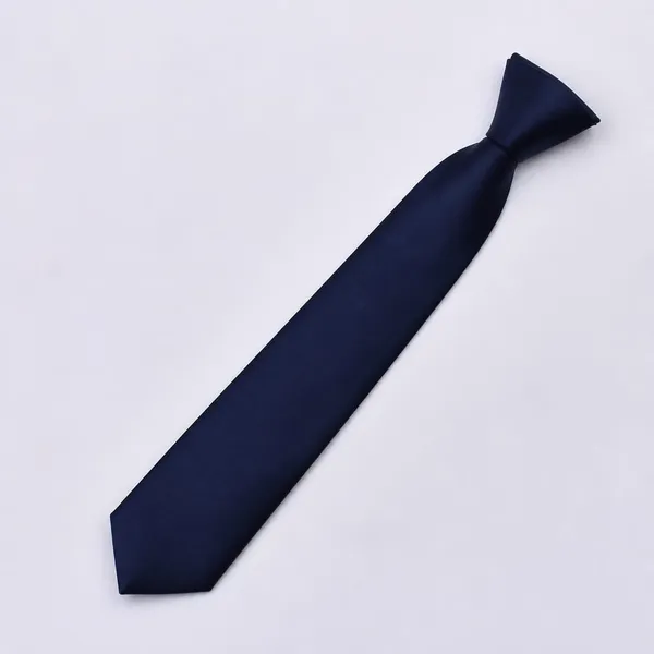Corbata escolar azul oscuro lisa, doblada sobre fondo blanco. La del Guimarc va contramarcada con el escudo del colegio